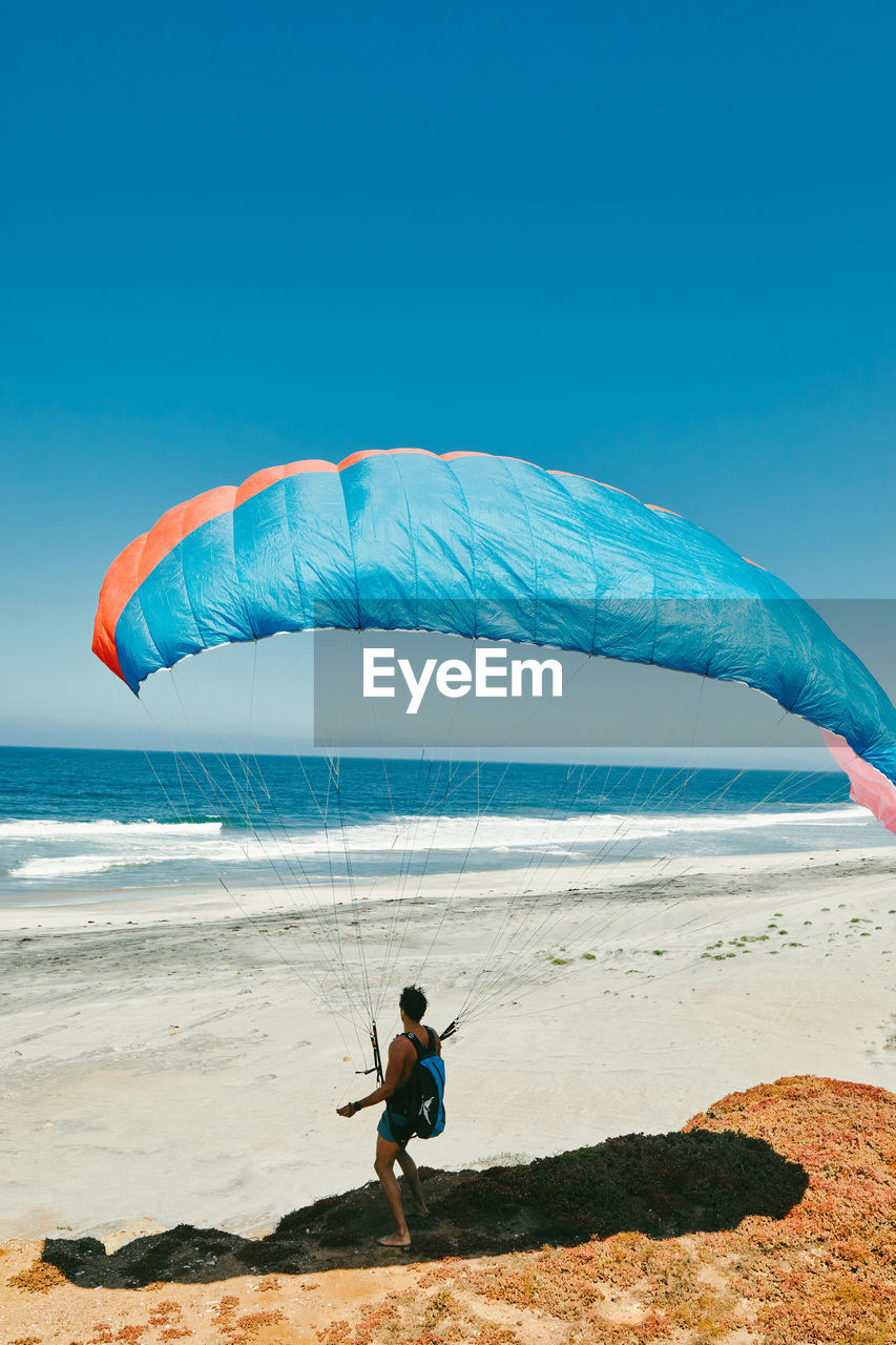 Young man paragliding on beach of paciifc coast in baja, mexico.