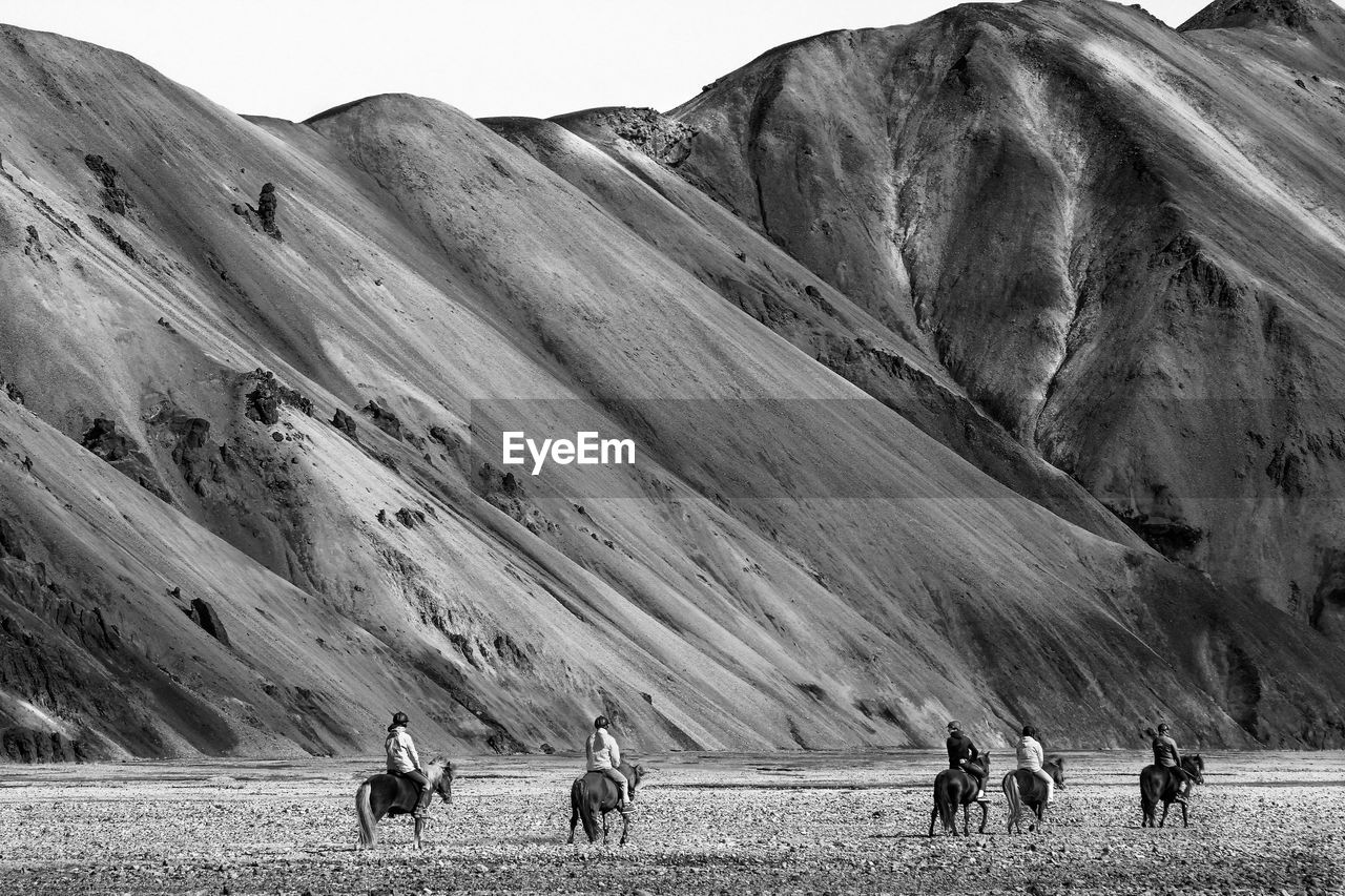Rear view of people riding horses at landmannalaugar