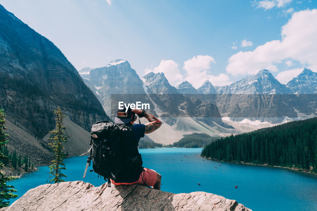 MAN PHOTOGRAPHING AT MOUNTAIN AGAINST SKY