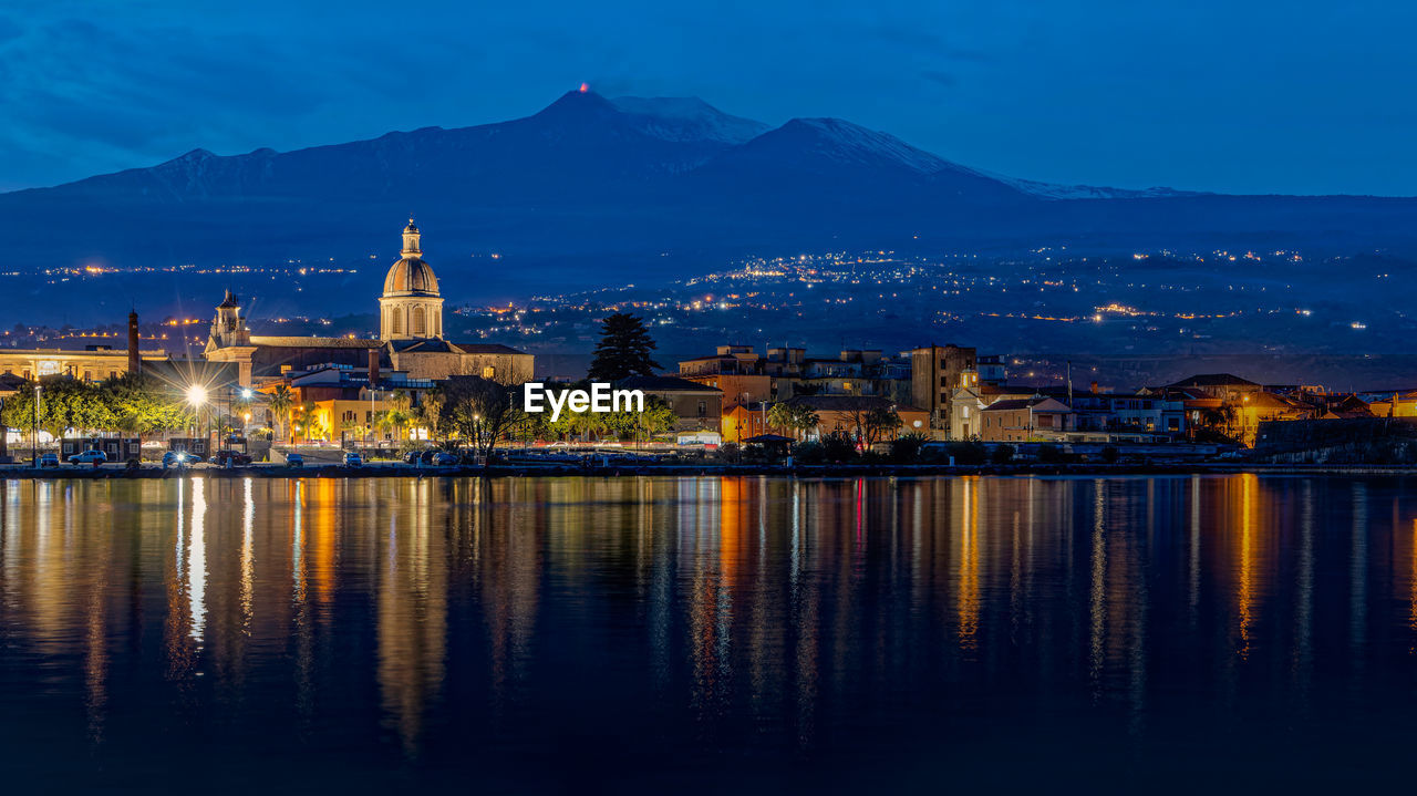 The city of riposto illuminated in the sky of the blue hour after sunset