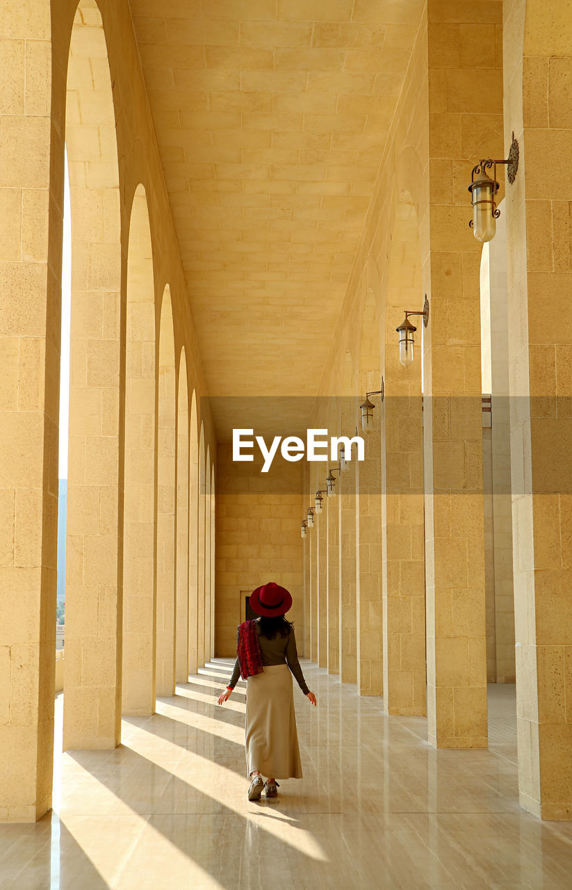 Vertical image of a female visitor walking in the marble corridor