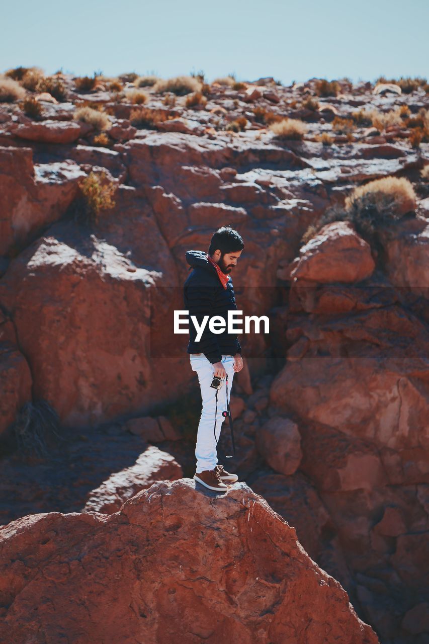 Man standing on rock against sky