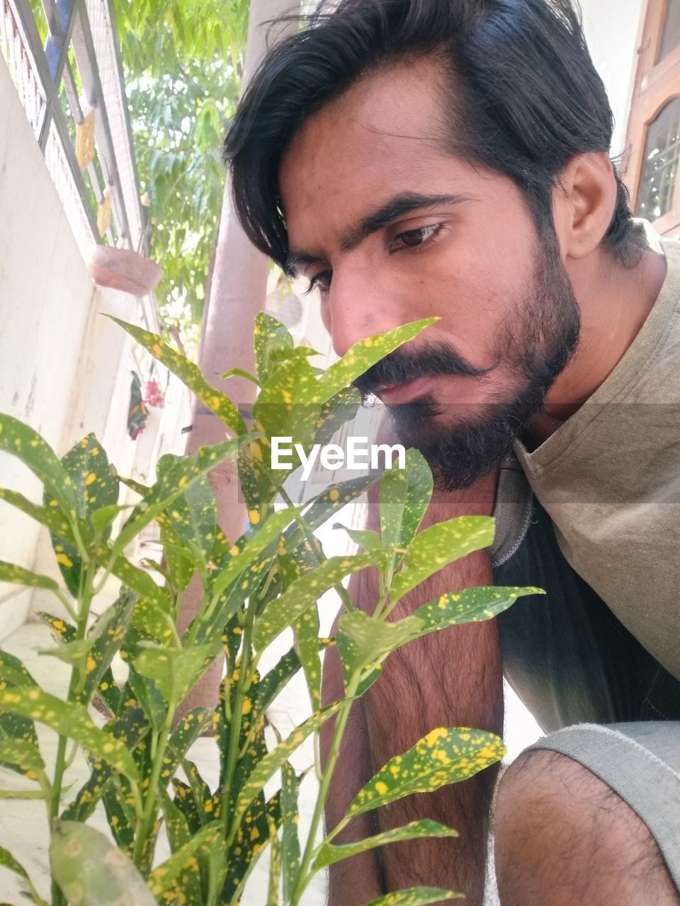 one person, adult, beard, facial hair, plant, men, portrait, nature, lifestyles, headshot, growth, human hair, young adult, leisure activity, flower, looking, person, day, casual clothing, outdoors, leaf, plant part, food and drink, gardening, architecture, front view, holding, stubble, human face, contemplation, food, brown hair, freshness, black hair, hairstyle