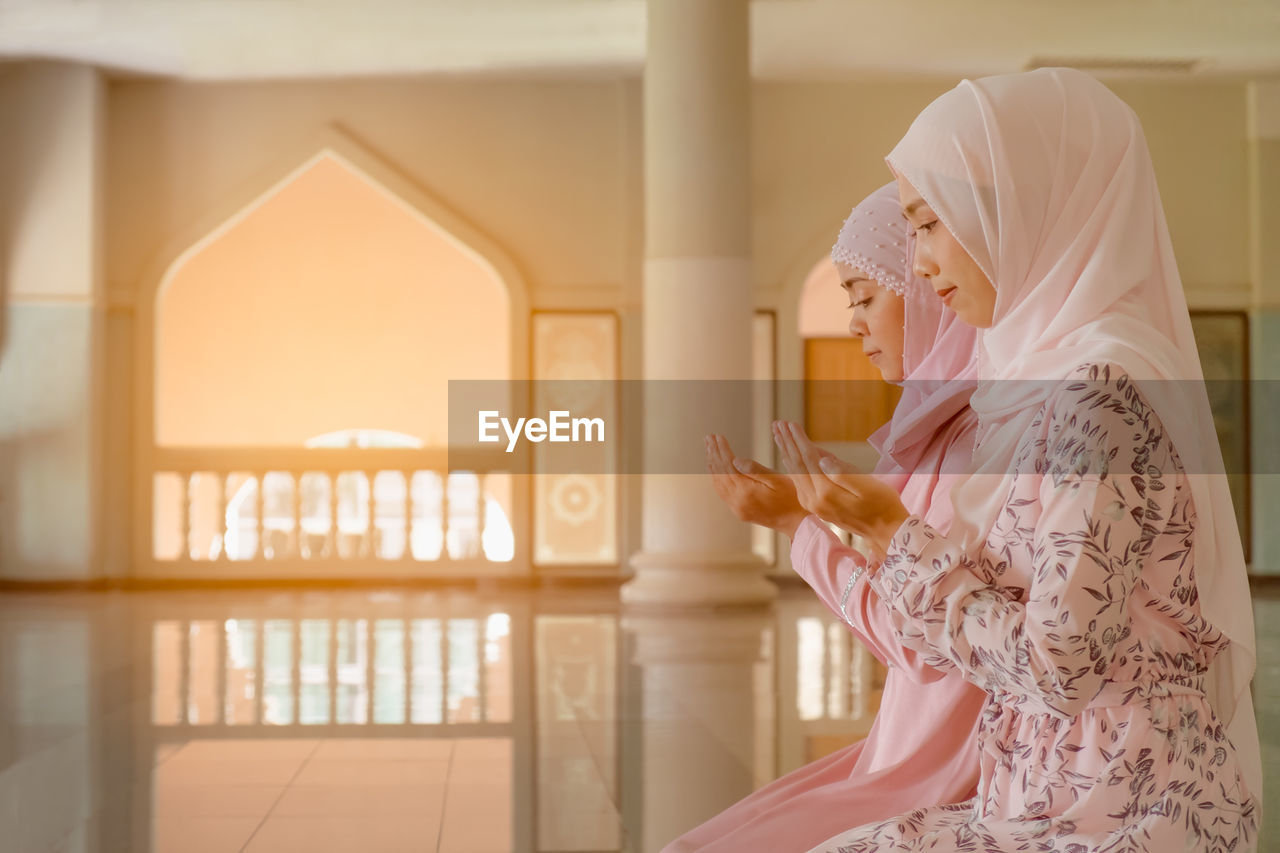 Side view of women praying at mosque