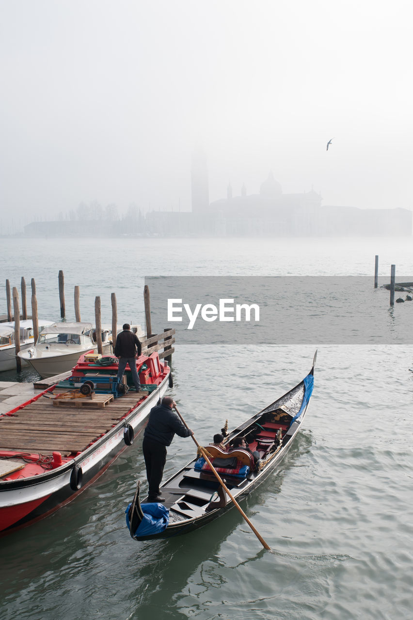 Rear view of men on gondola at san giorgio maggiore during foggy weather