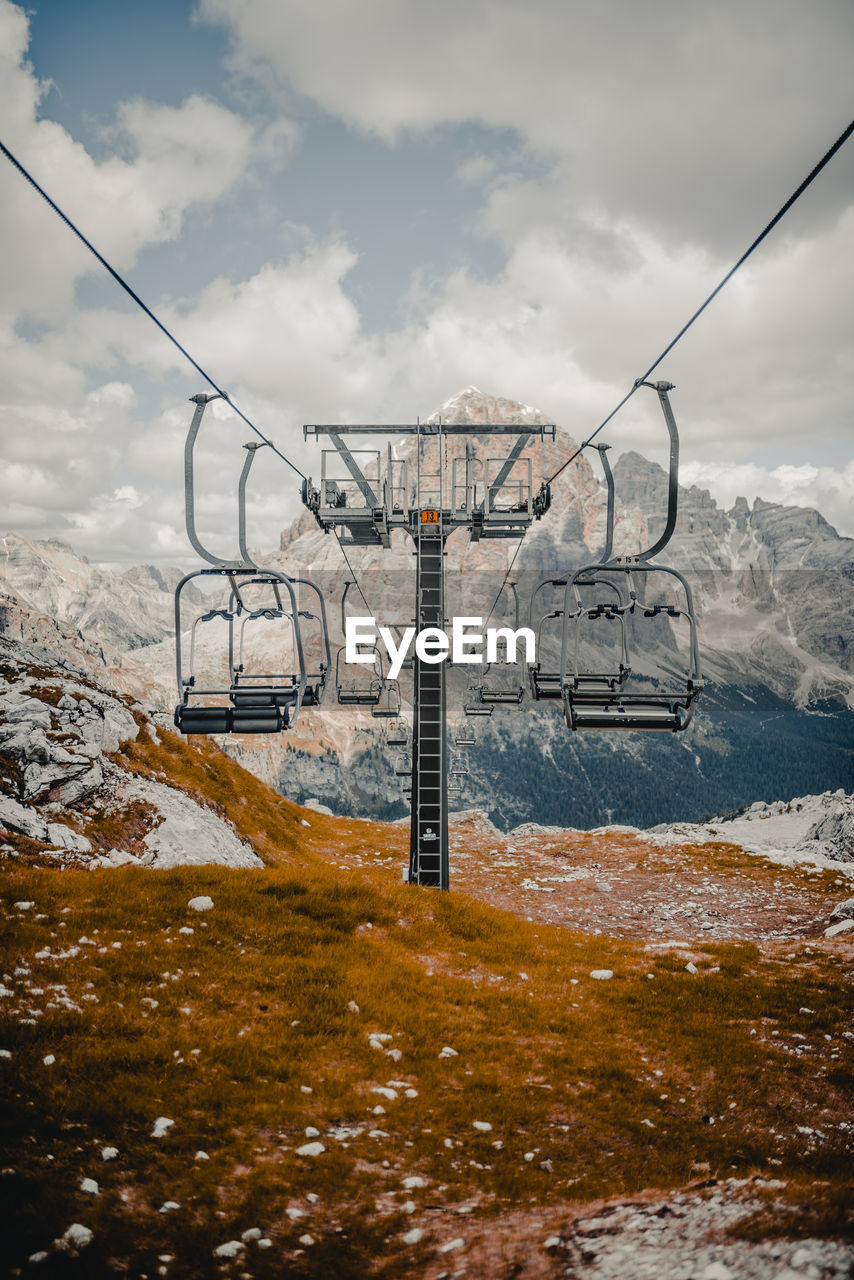 Overhead cable cars against cloudy sky during winter