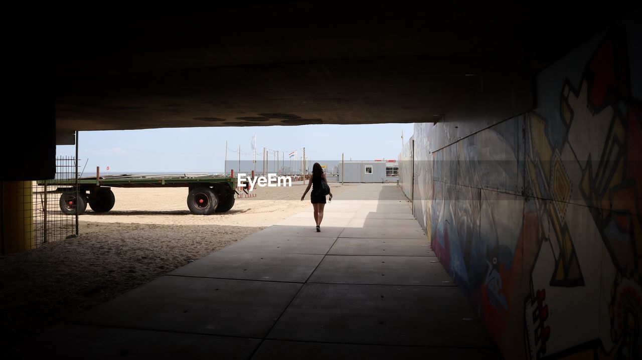 REAR VIEW OF PERSON WALKING ON CORRIDOR