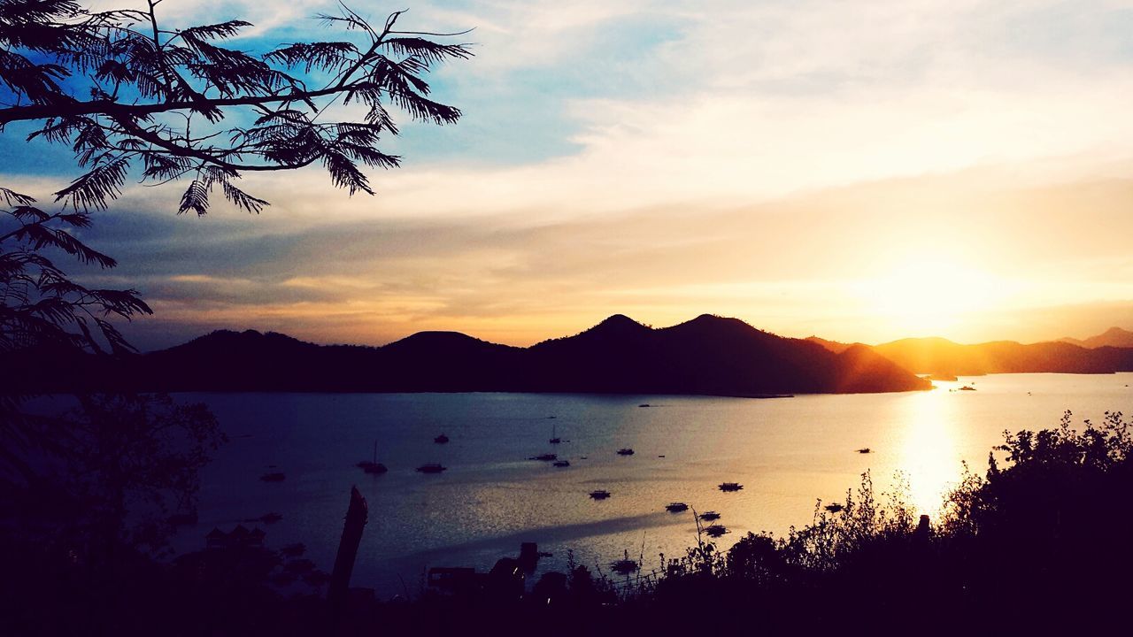 Scenic view of lake and silhouette mountains against sky during sunset