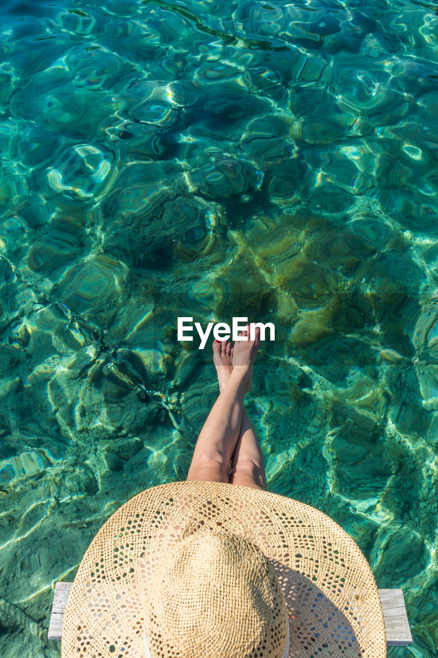 Directly above shot of woman wearing hat sitting by sea