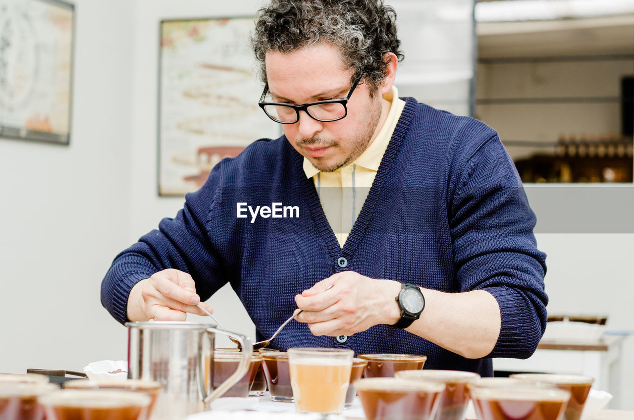 MIDSECTION OF MAN HOLDING ICE CREAM WITH TABLE