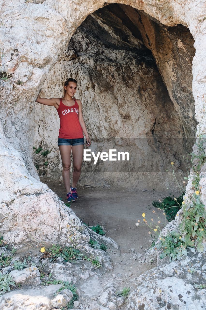 Young woman walking through cave tunnel