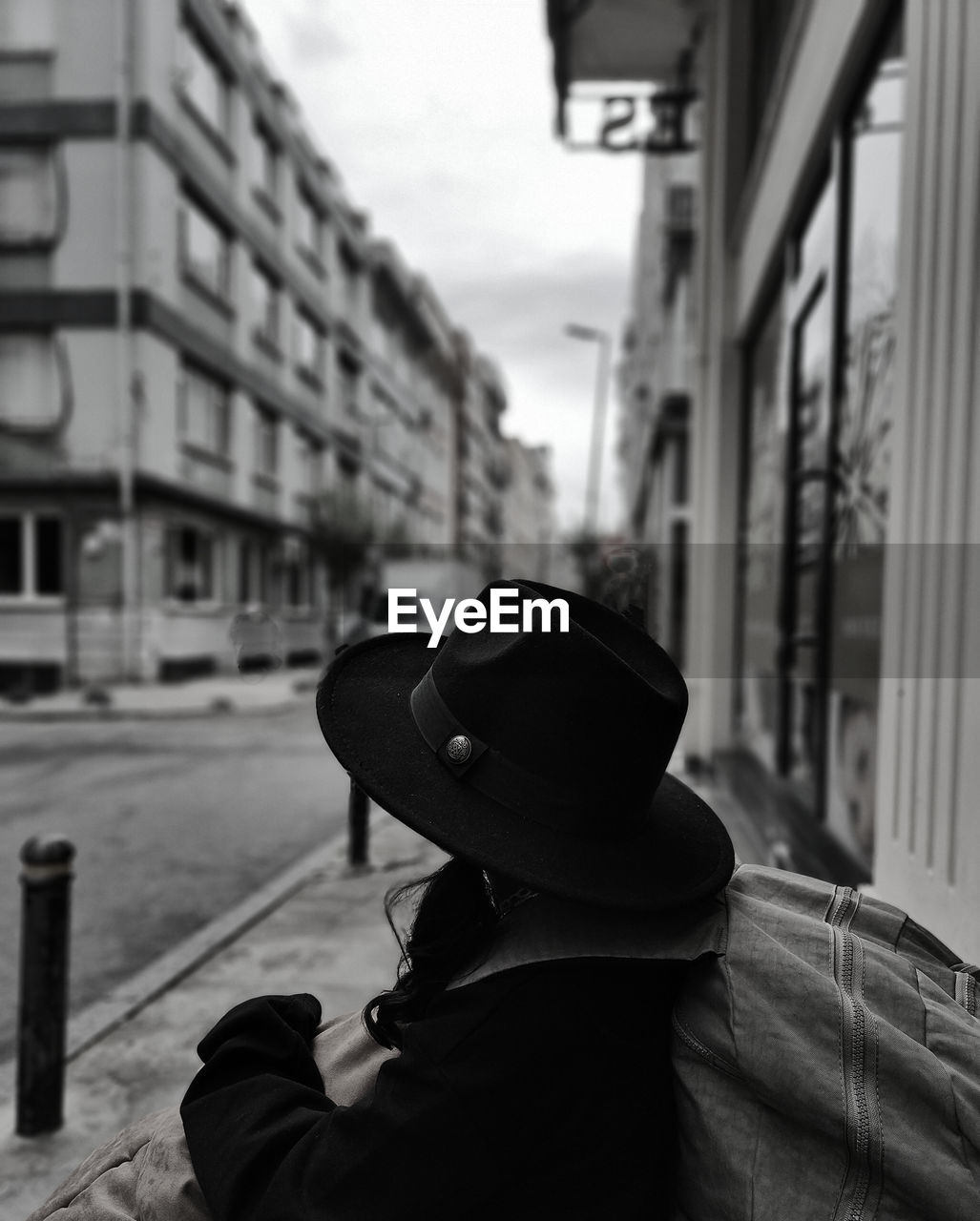 rear view of man wearing hat standing on street in city