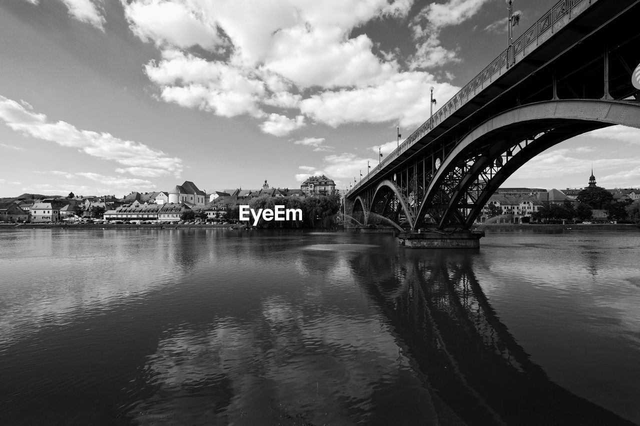 Bridge over river against cloudy sky