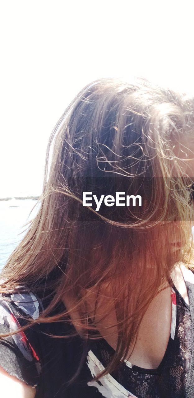 CLOSE-UP PORTRAIT OF YOUNG WOMAN WITH HAIR AGAINST SKY