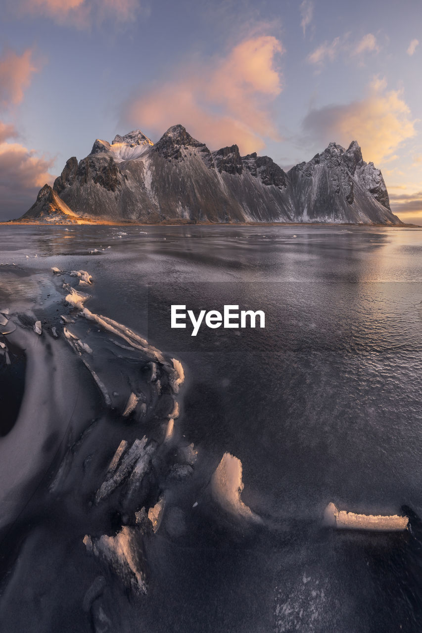 Spectacular view of massive snowy rocky formations surrounded by frozen endless sea during bright sundown