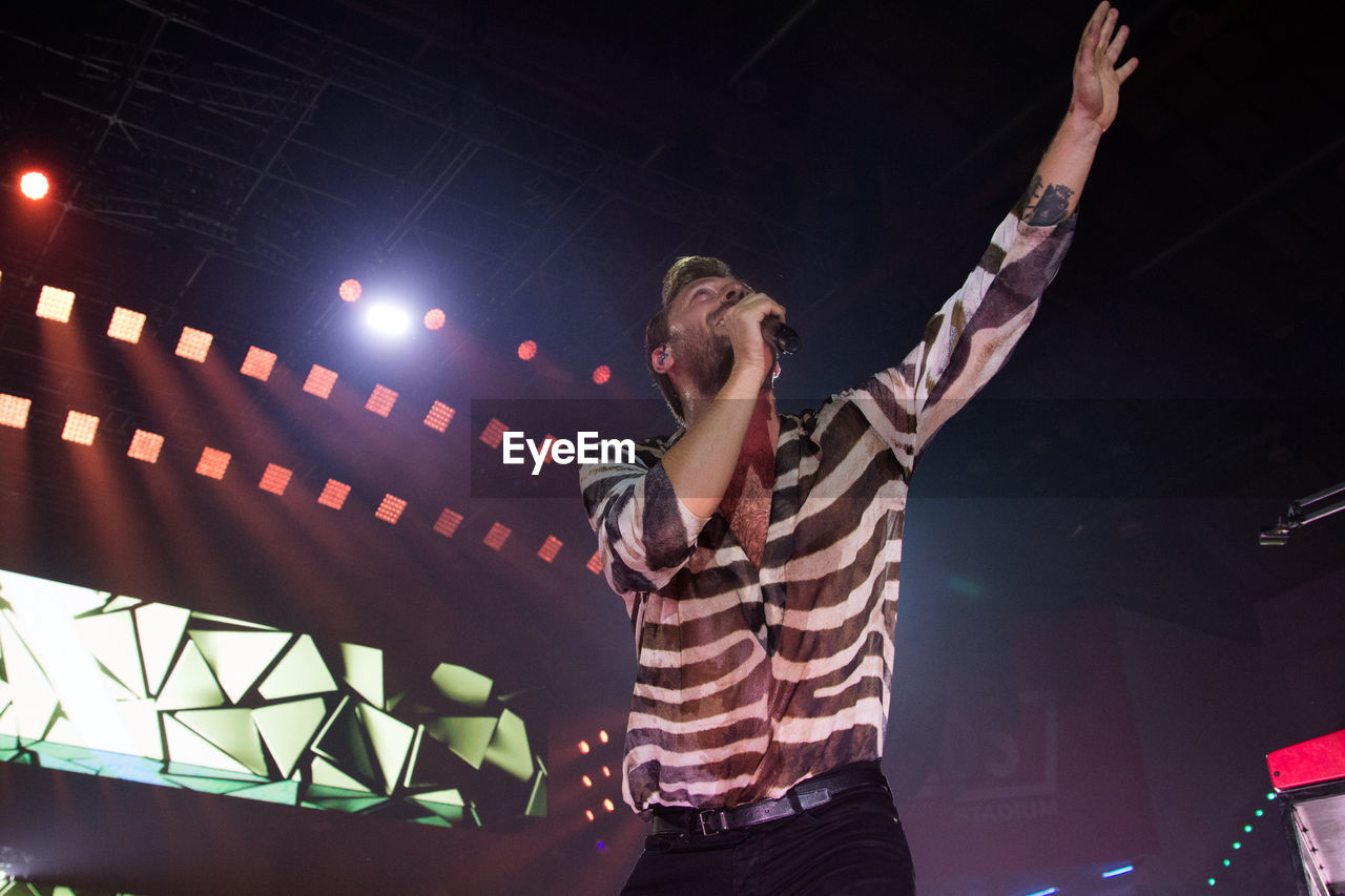 LOW ANGLE VIEW OF WOMAN WITH ARMS OUTSTRETCHED