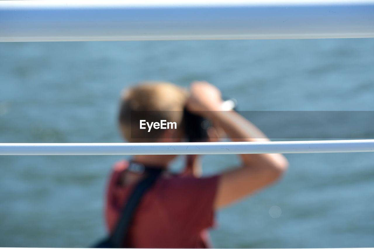 PORTRAIT OF WOMAN PHOTOGRAPHING SEA