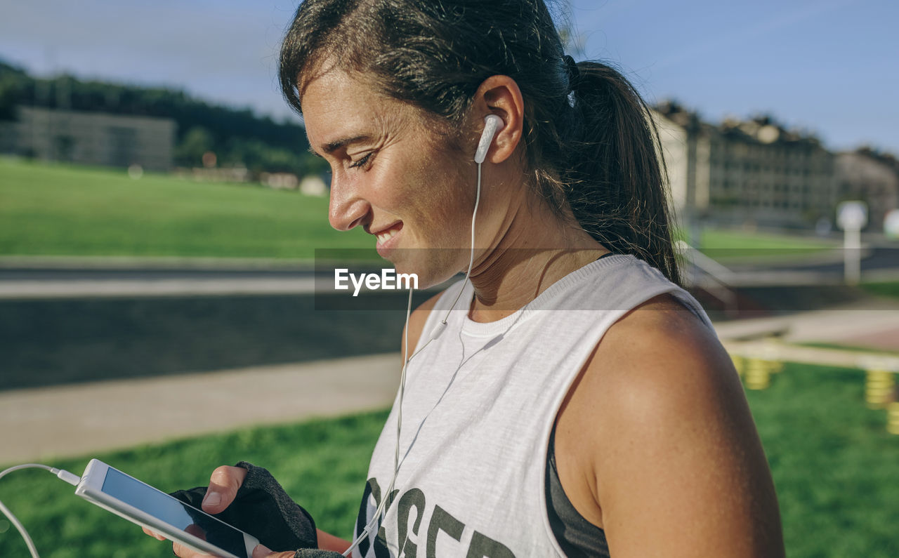 Side view of woman using phone at park