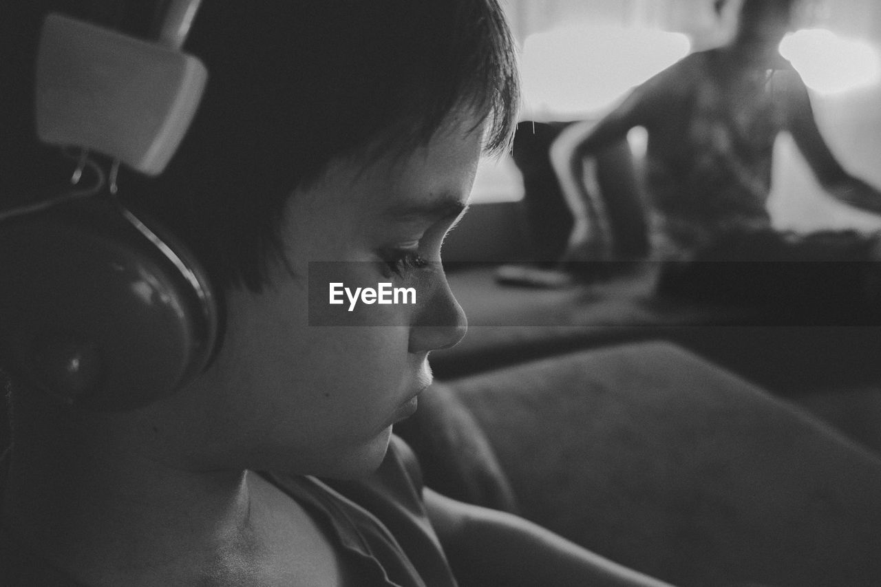 Close-up of boy wearing headphones while sitting on sofa