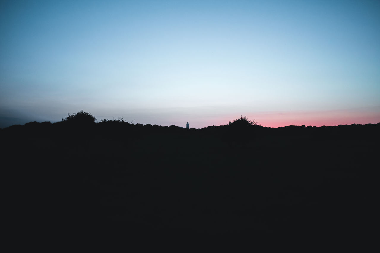 Silhouette landscape against clear sky at sunset