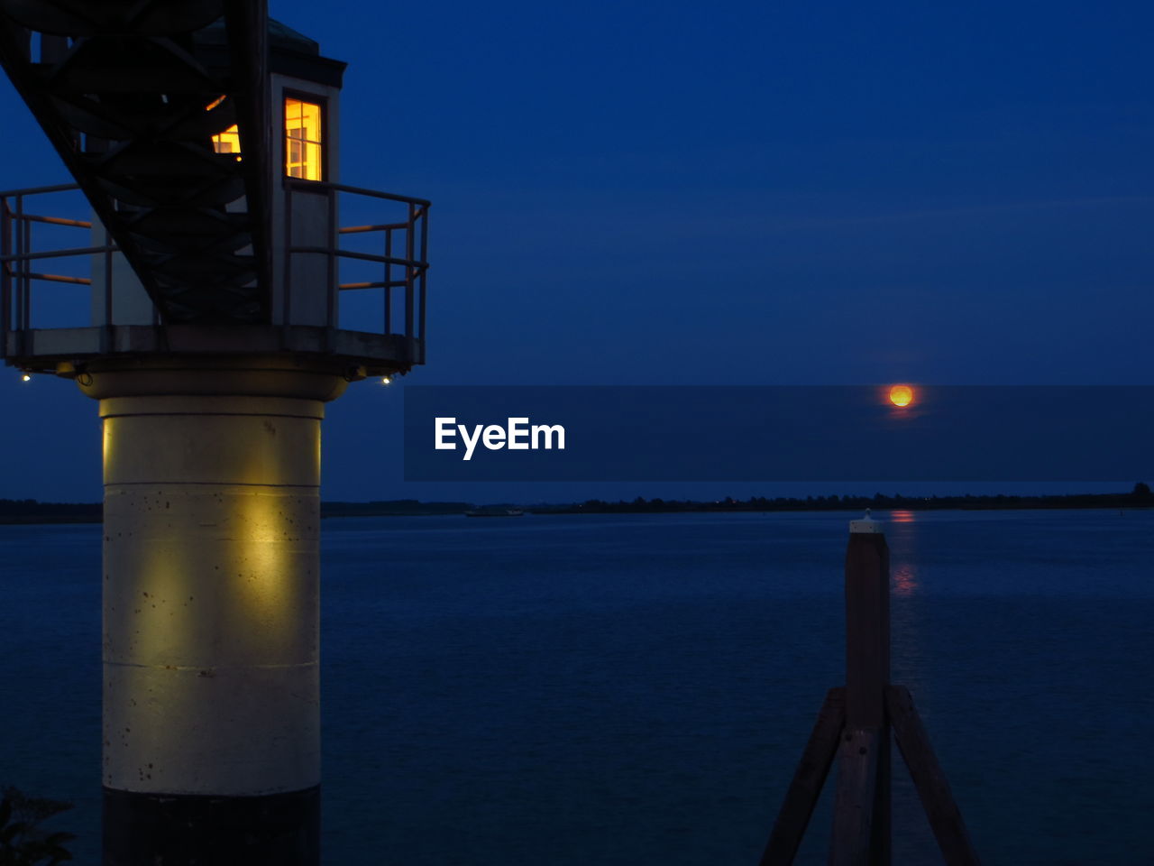 Lighthouse and lake against sky at dusk