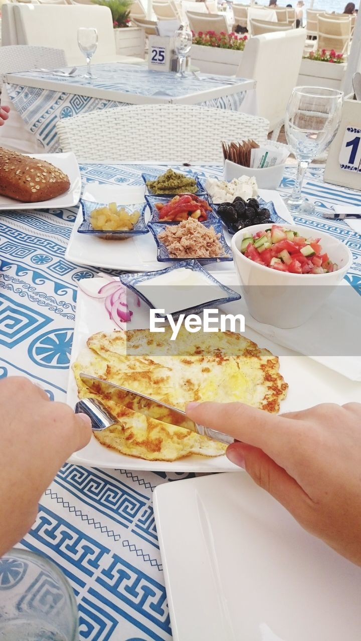 Cropped image of hand holding knife and fork against table