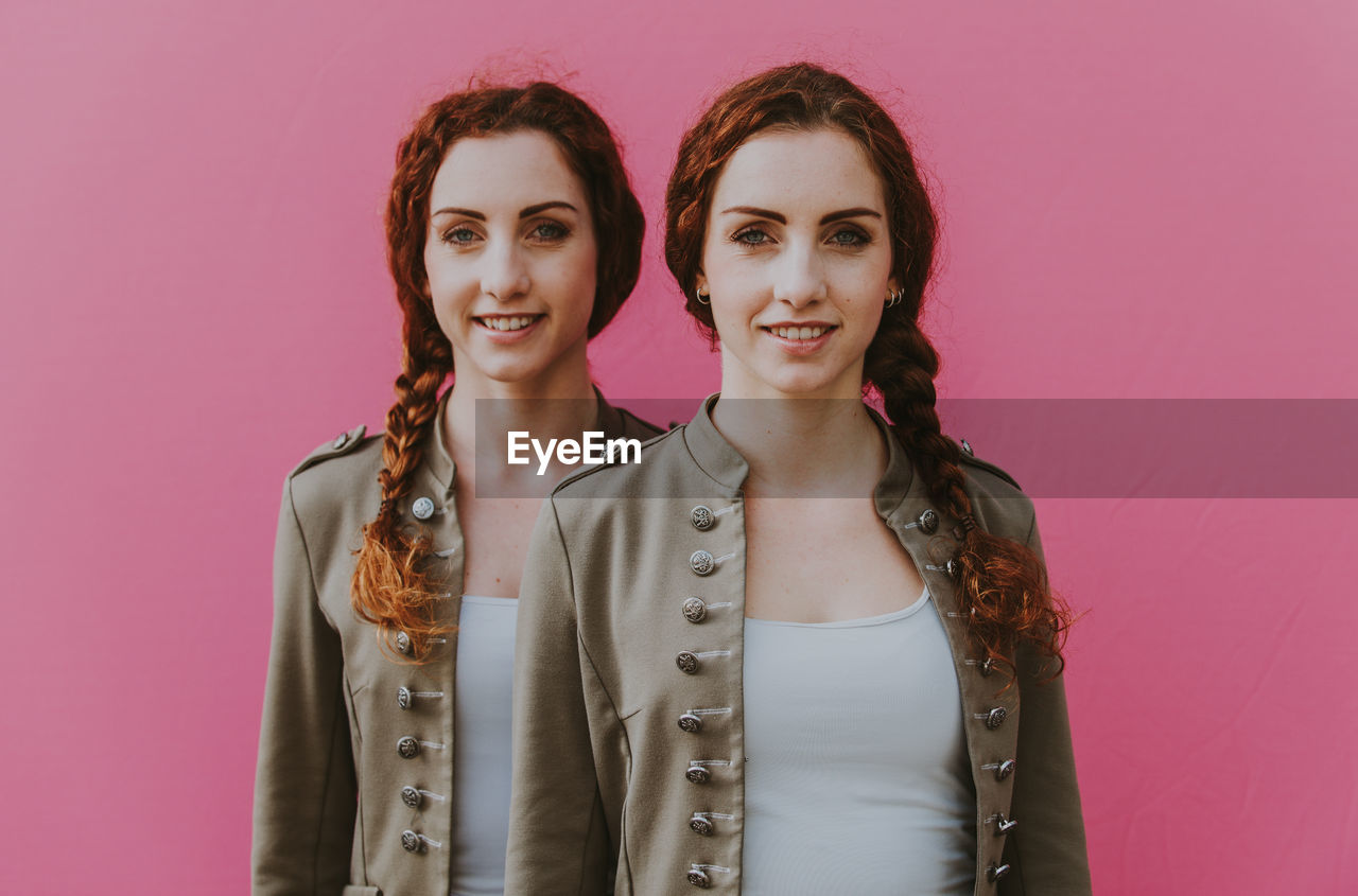 Portrait of smiling siblings against pink background