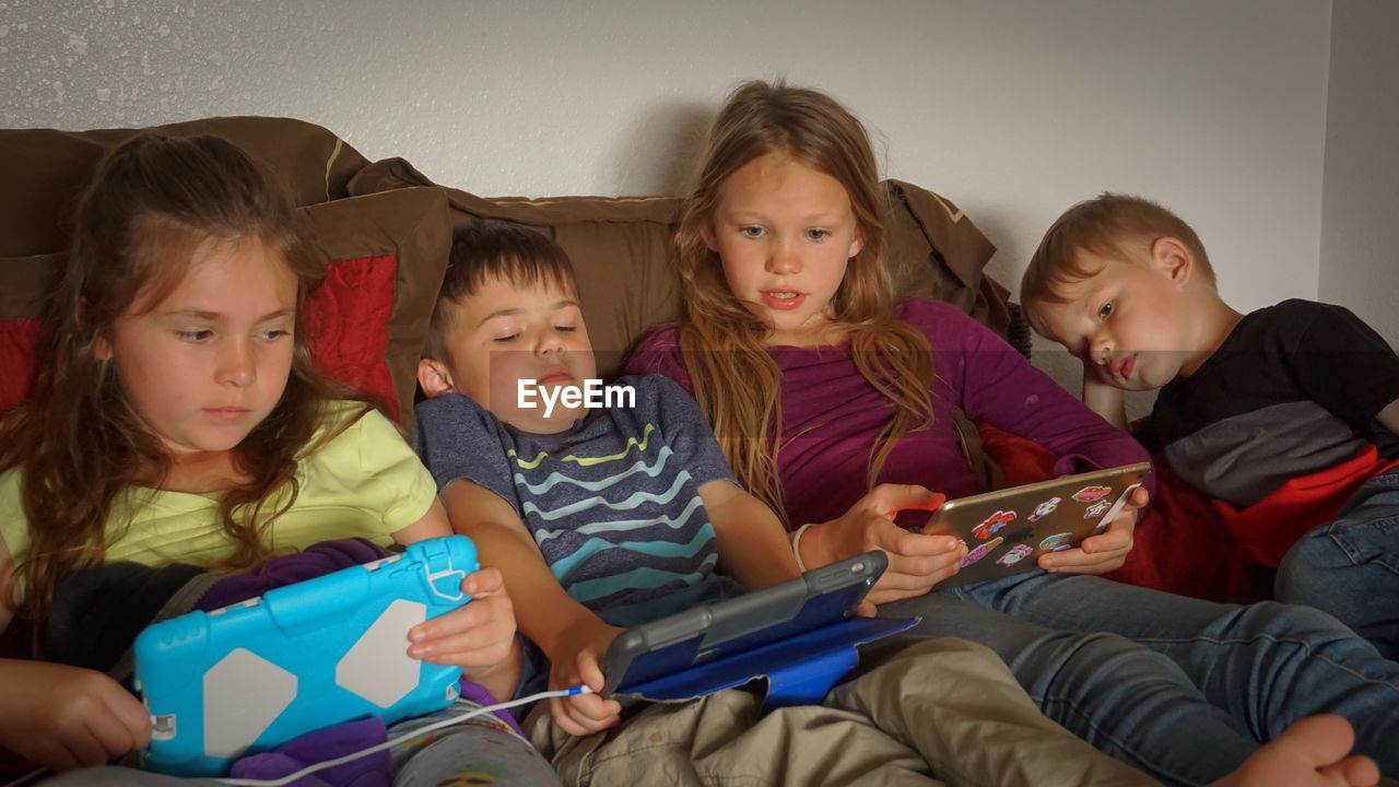 HAPPY SIBLINGS SITTING ON BED