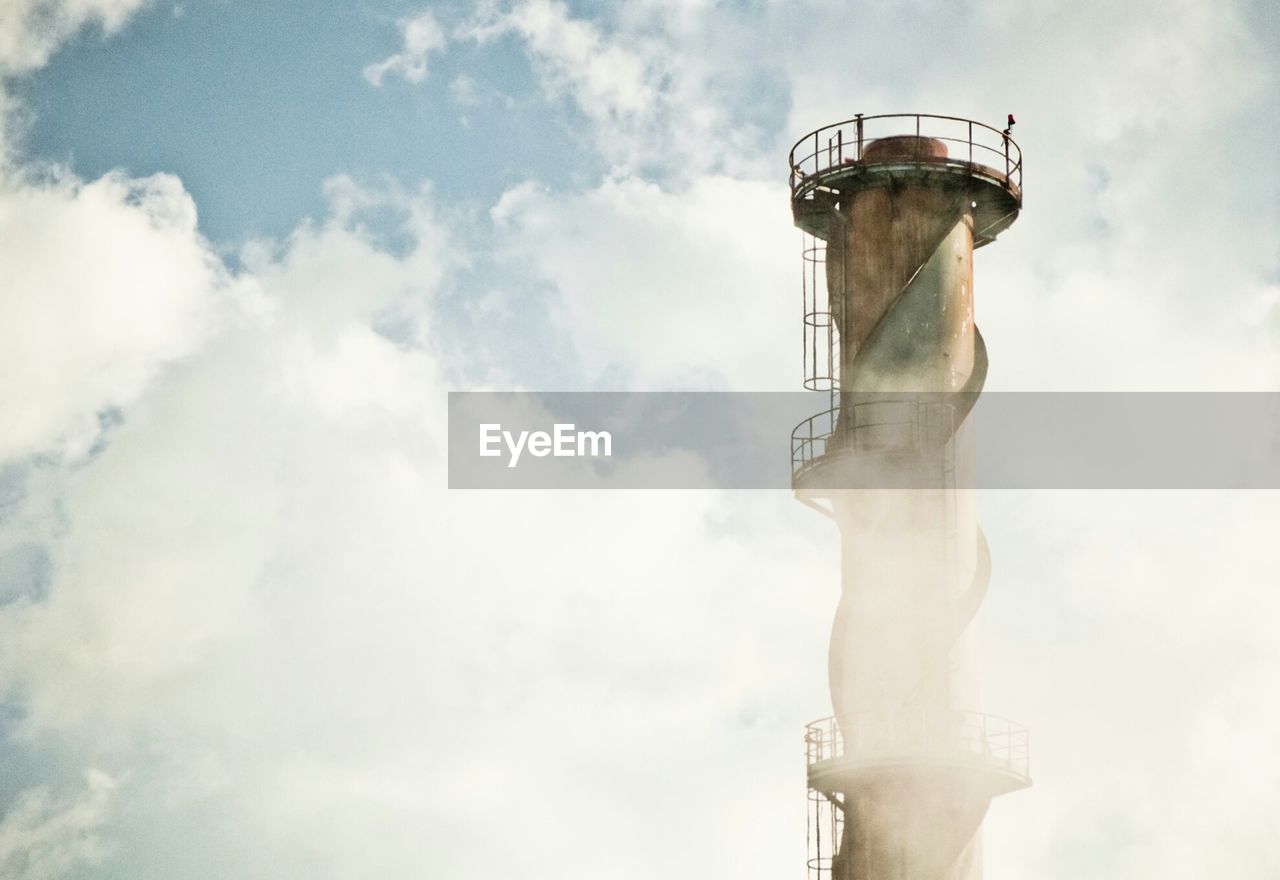 Smoke stack against cloudy sky