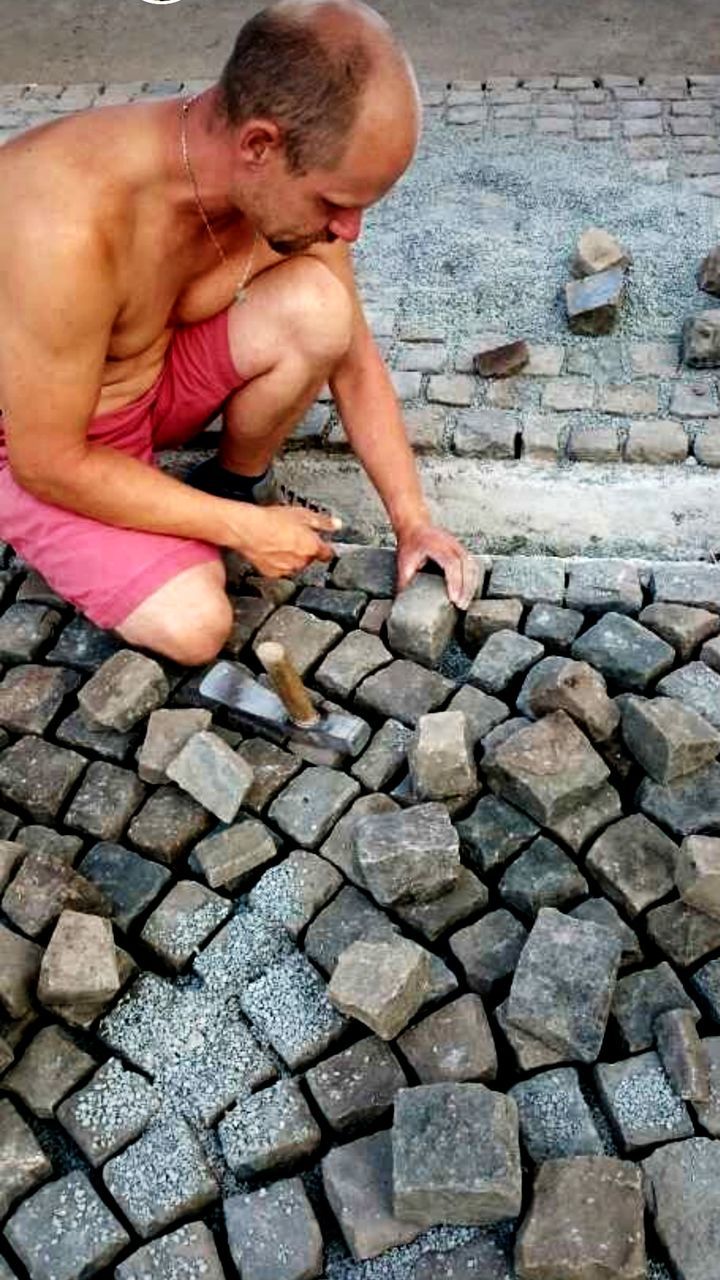 Full length of shirtless man working on street