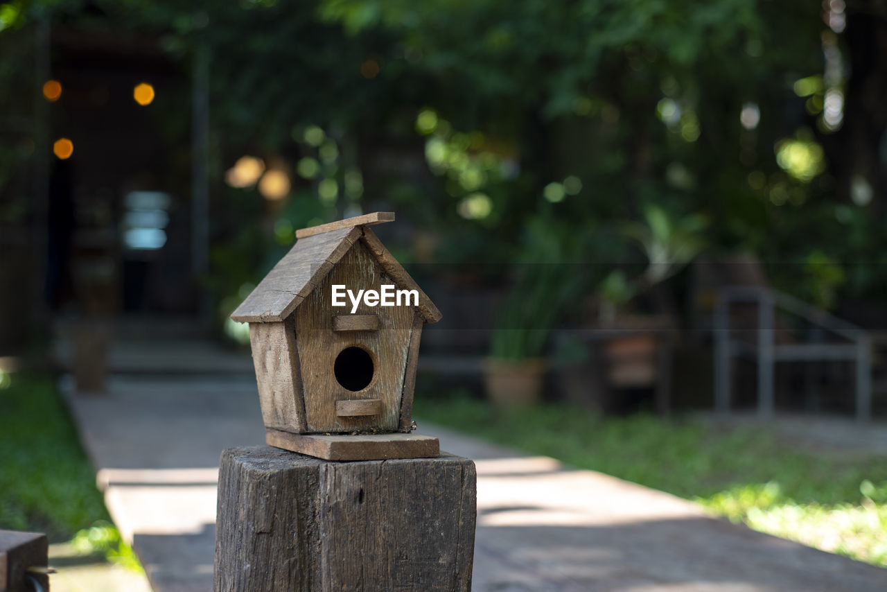 CLOSE-UP OF BIRDHOUSE AGAINST TREES