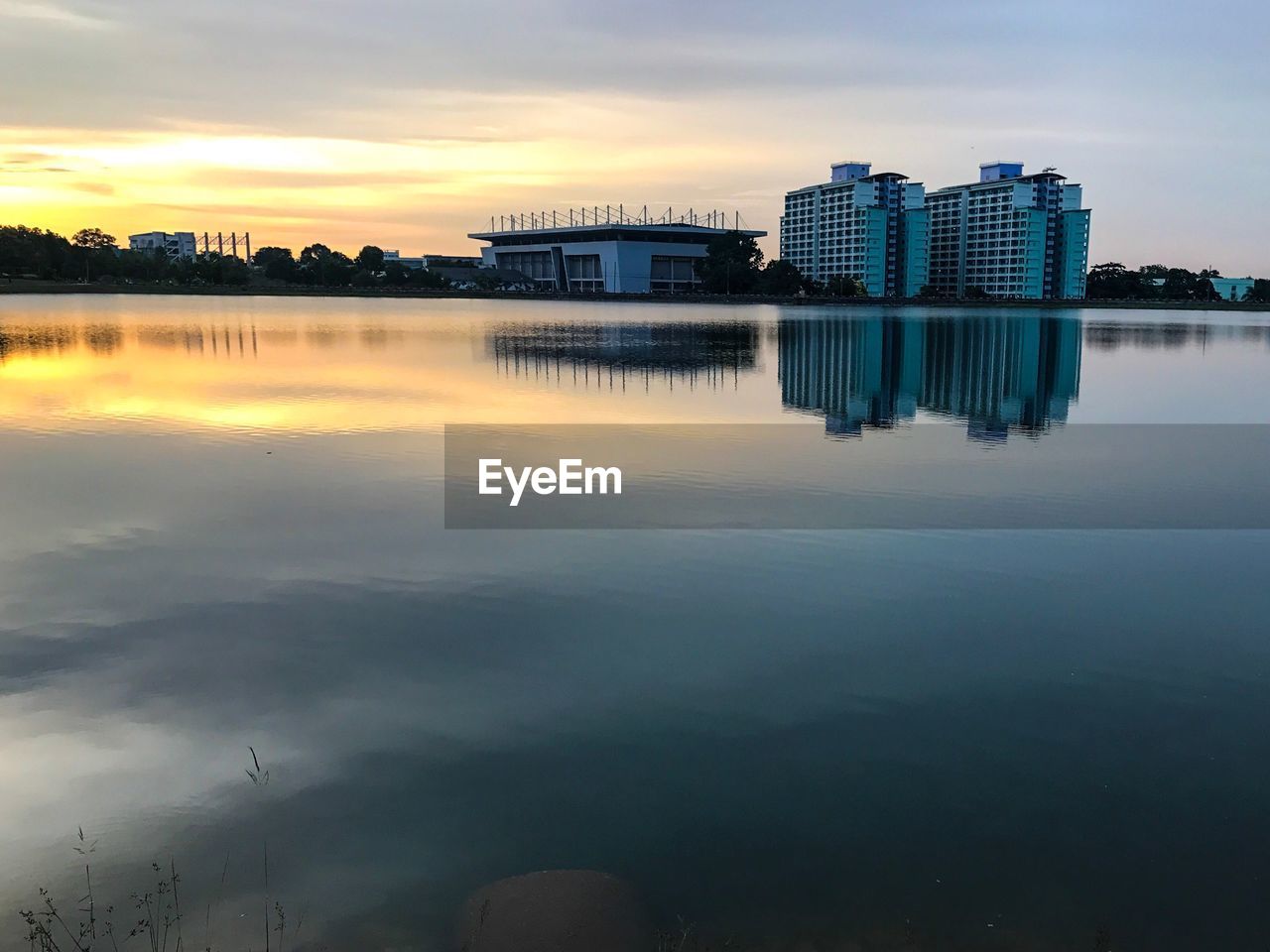 Reflection of buildings in lake against sky during sunset