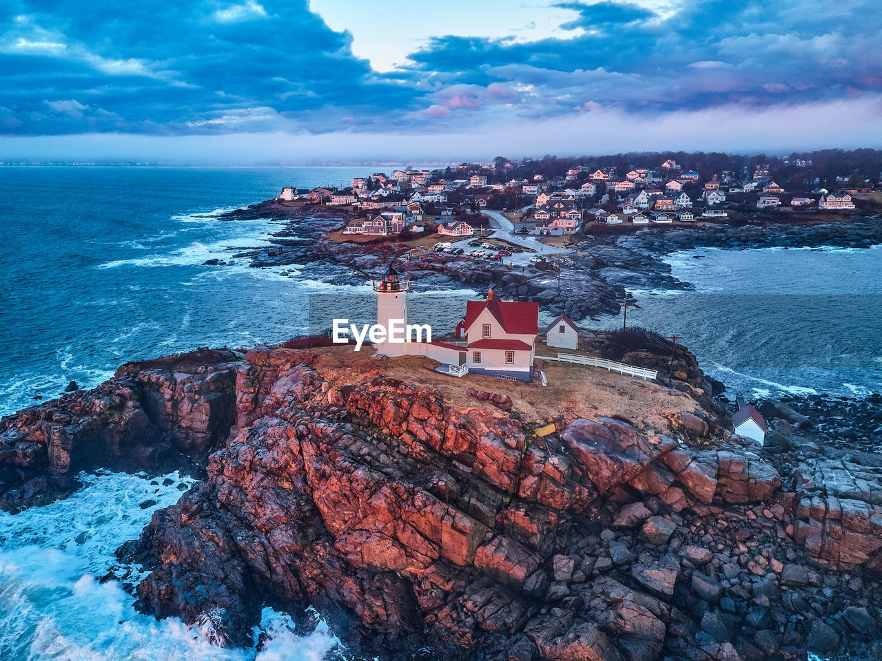 SCENIC VIEW OF SEA BY ROCKS AND BUILDINGS AGAINST SKY