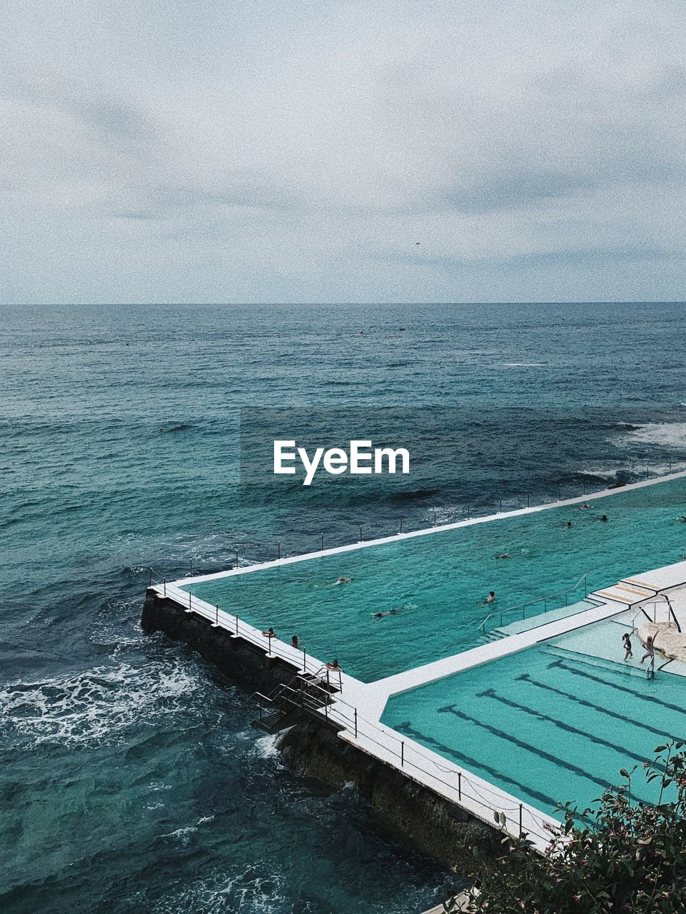 HIGH ANGLE VIEW OF SWIMMING POOL AGAINST SEA