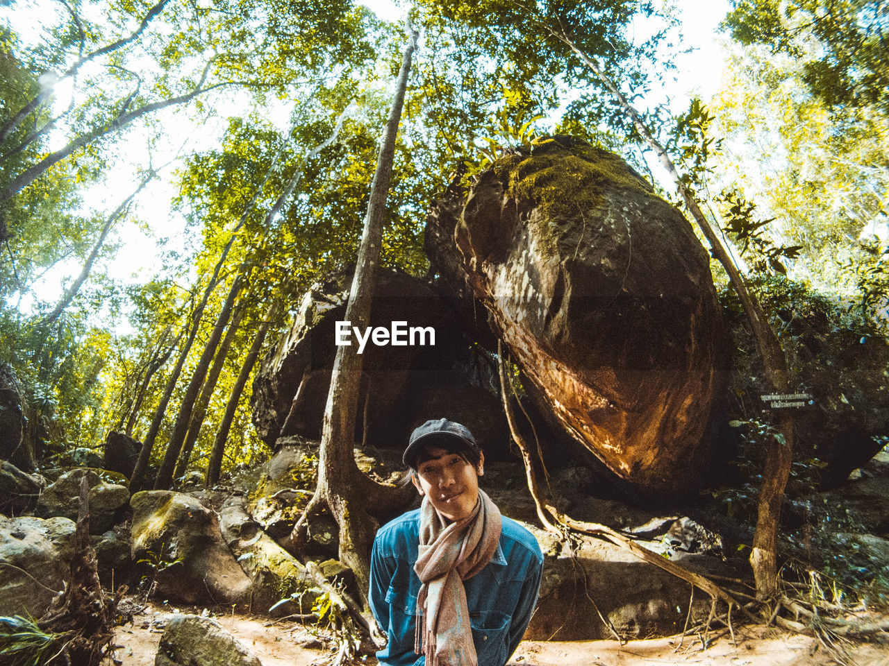 Portrait of man standing by rocks in forest