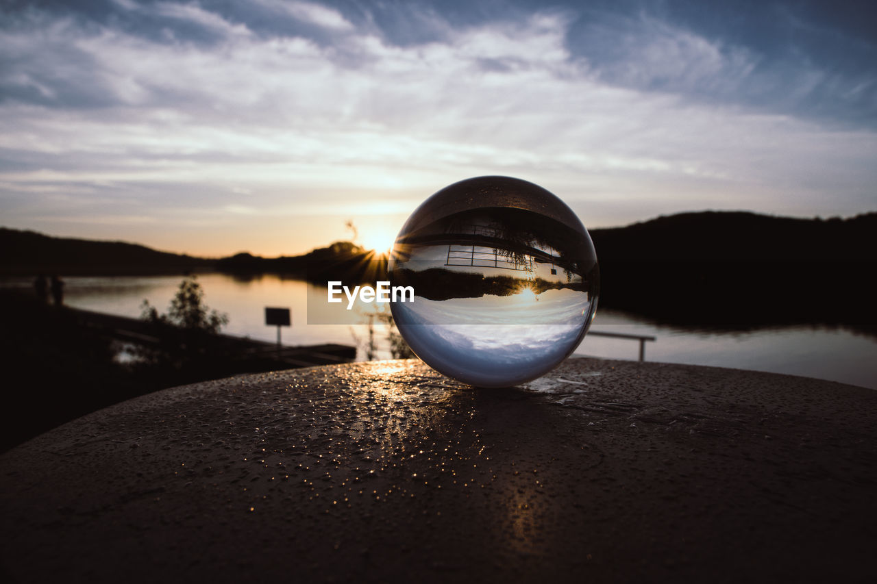 CLOSE-UP OF CRYSTAL BALL ON LAKE DURING SUNSET