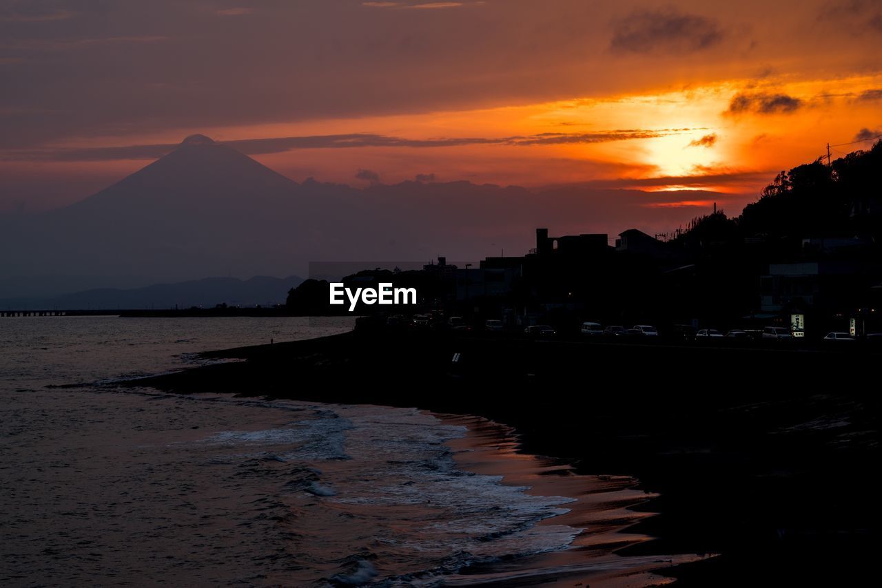 Scenic view of beach with silhouette mt fuji in background during sunset