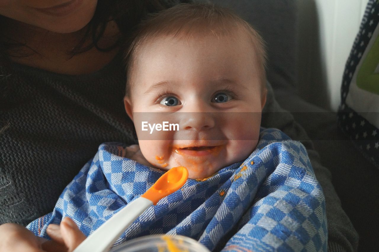 Portrait of happy baby boy fed by mother