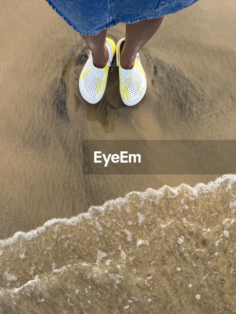 beach, sand, blue, land, low section, human leg, shoe, water, one person, high angle view, leisure activity, lifestyles, nature, footwear, day, sea, casual clothing, sports, jeans, surfing, motion, limb, vacation, trip, outdoors, standing, adult, human limb, yellow, water sports, holiday, men, white, human foot, women, sunlight, personal perspective, clothing, relaxation, wave