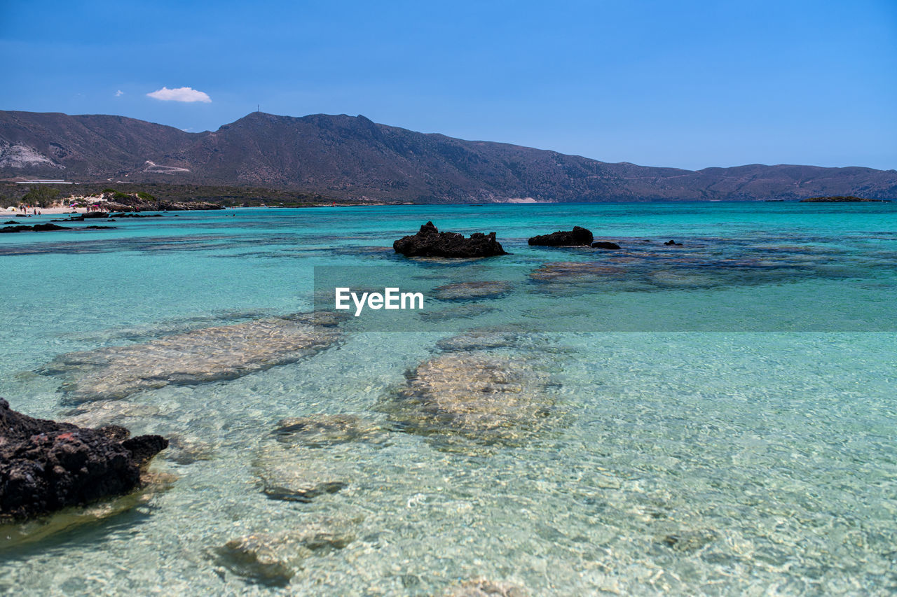 SCENIC VIEW OF SEA AND MOUNTAINS AGAINST BLUE SKY