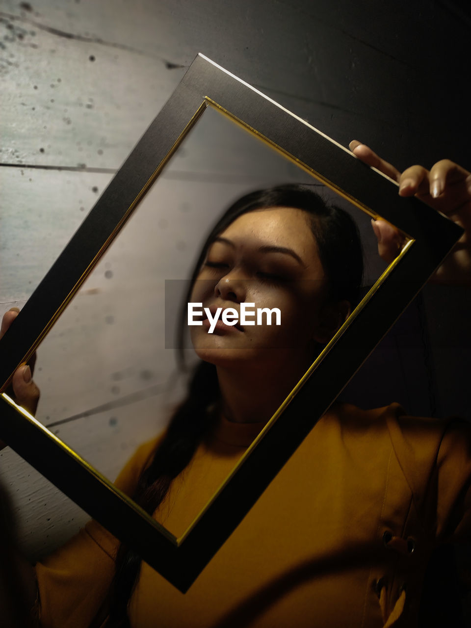 Portrait of young woman holding picture frame