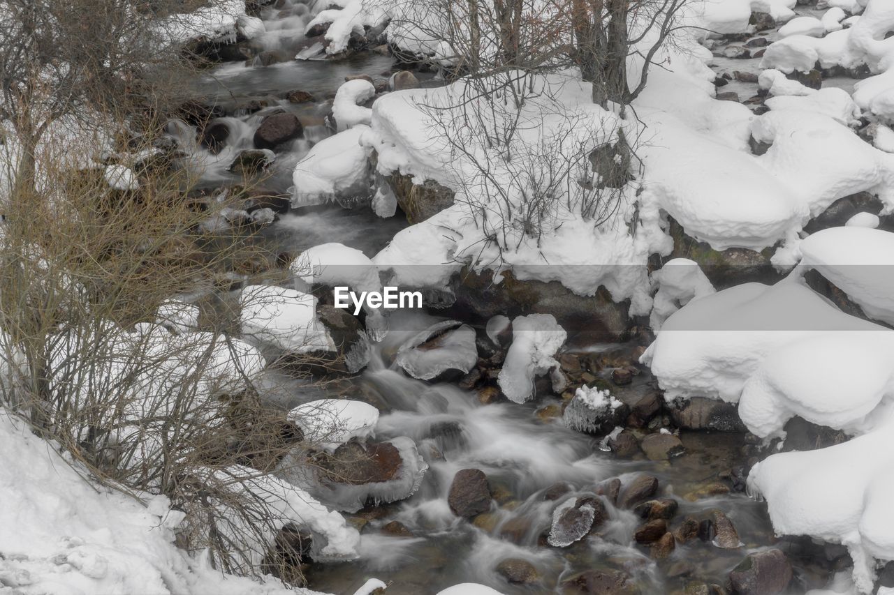 winter, cold temperature, snow, nature, tree, beauty in nature, land, plant, no people, scenics - nature, environment, freezing, frozen, tranquility, day, white, rock, landscape, outdoors, non-urban scene, stream, tranquil scene, high angle view, forest, water, field, ice