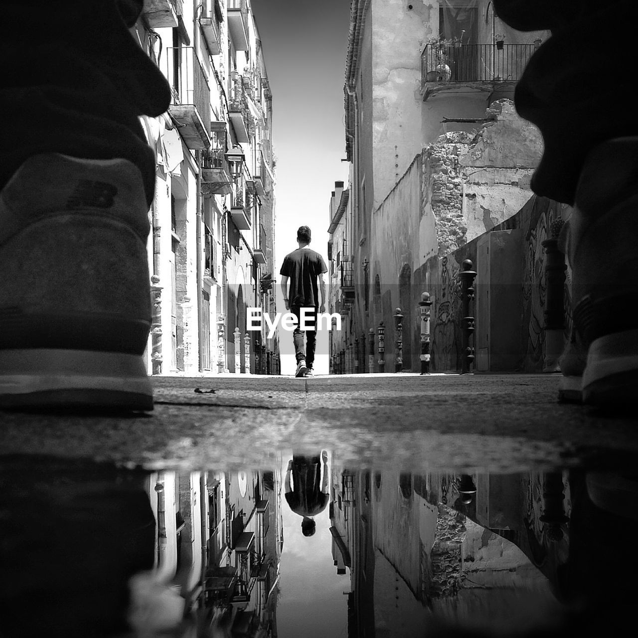 Rear view of man walking on pathway along buildings