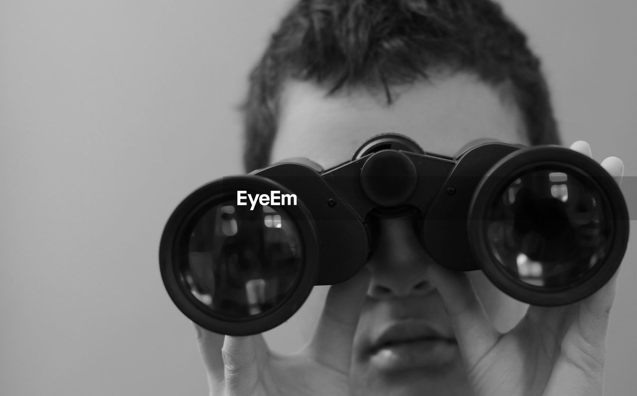 Boy looking through binoculars on grey background with people stock image stock photo