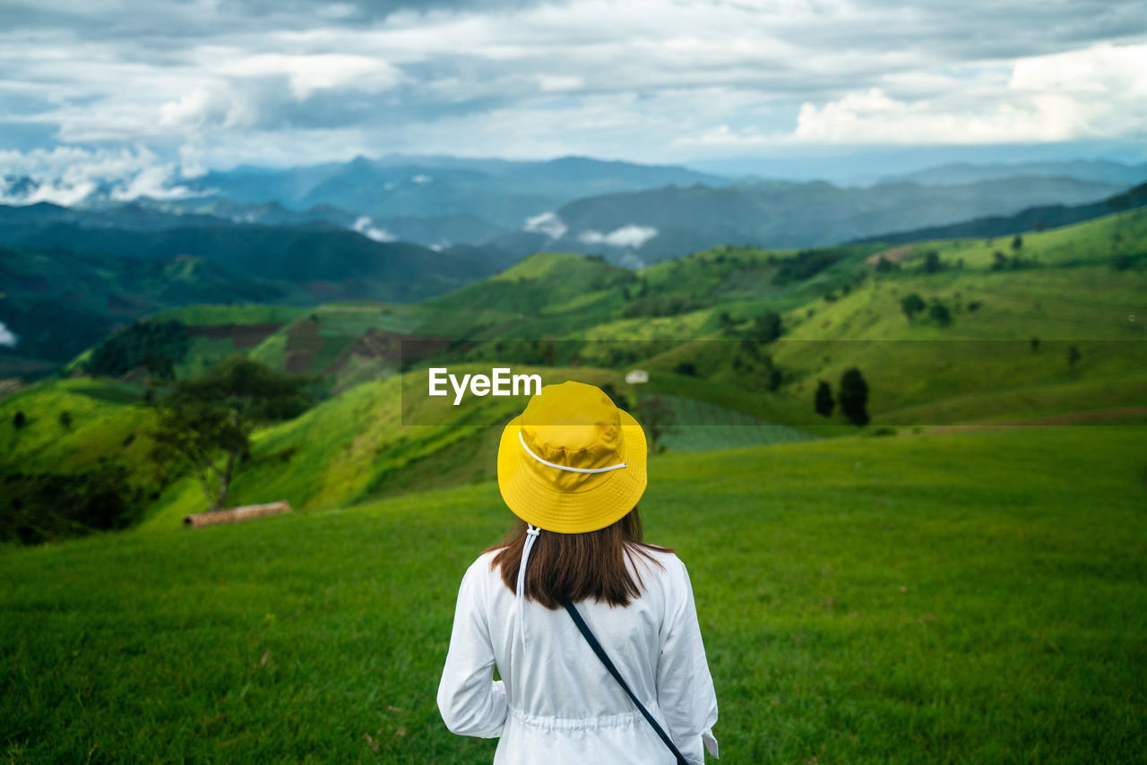 REAR VIEW OF WOMAN WITH UMBRELLA ON LANDSCAPE