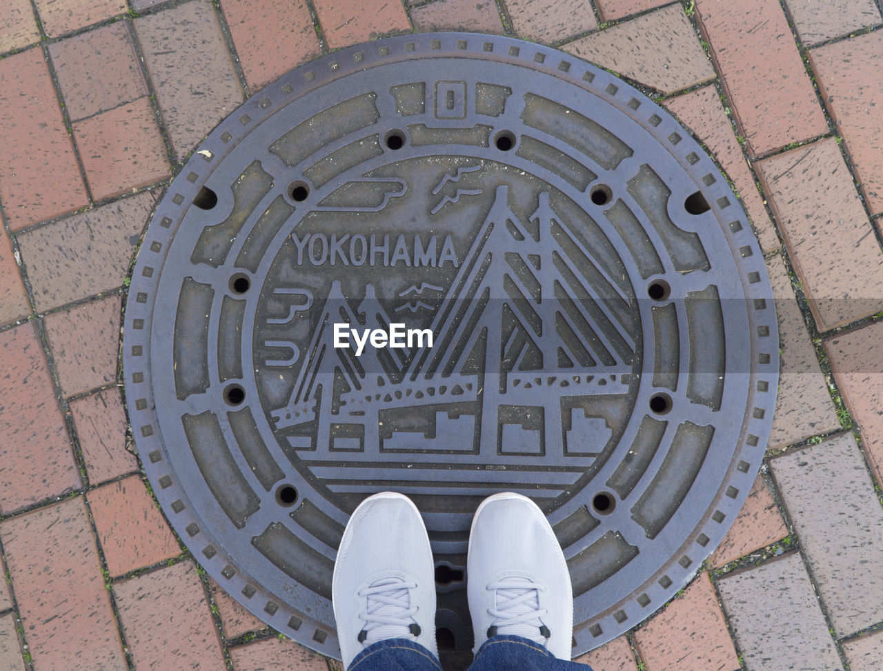 Low section of man standing on manhole