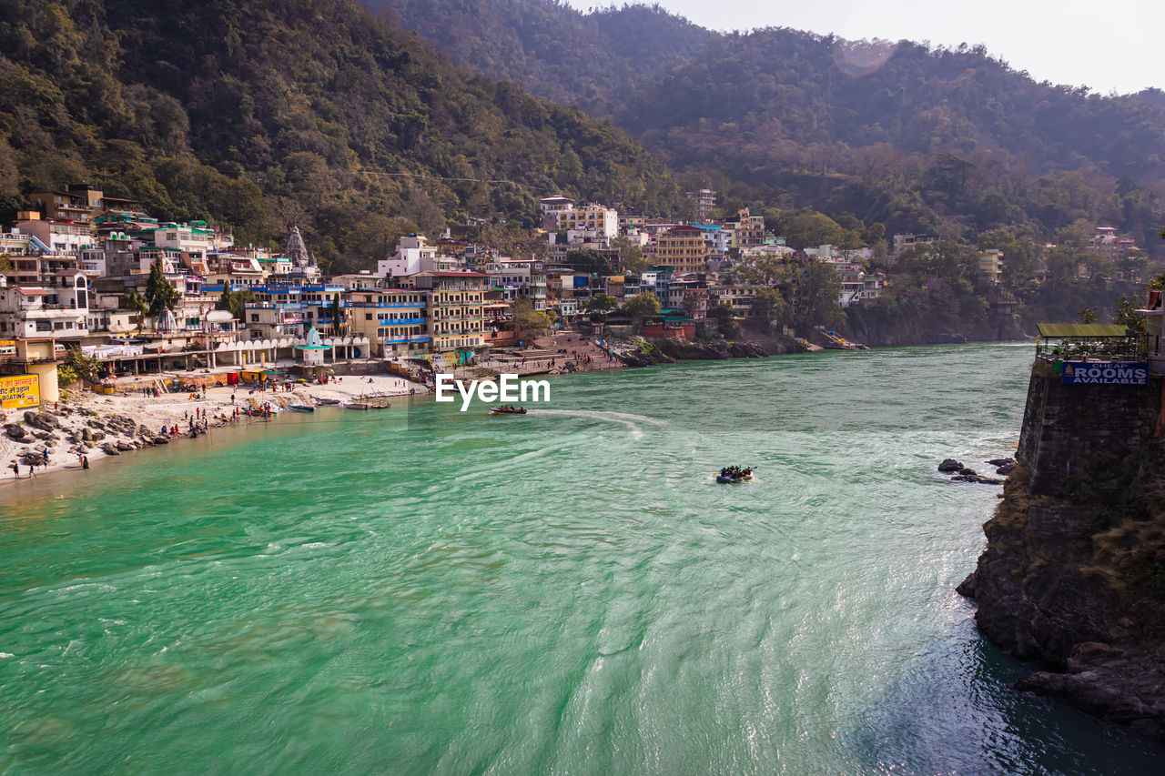 City at river bank with mountain background at day from flat angle