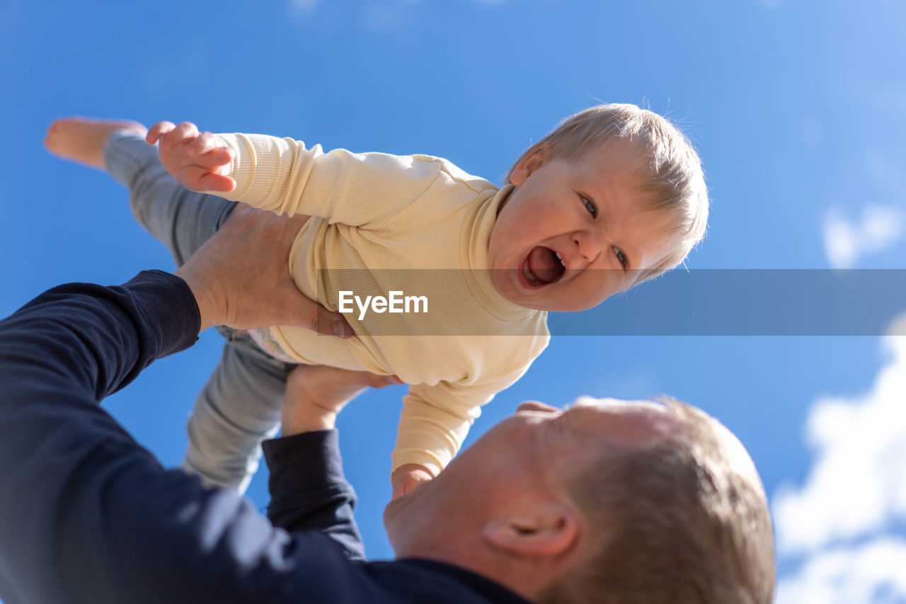Young father holding cute little daughter in front of blue sky. father day, concept game with child