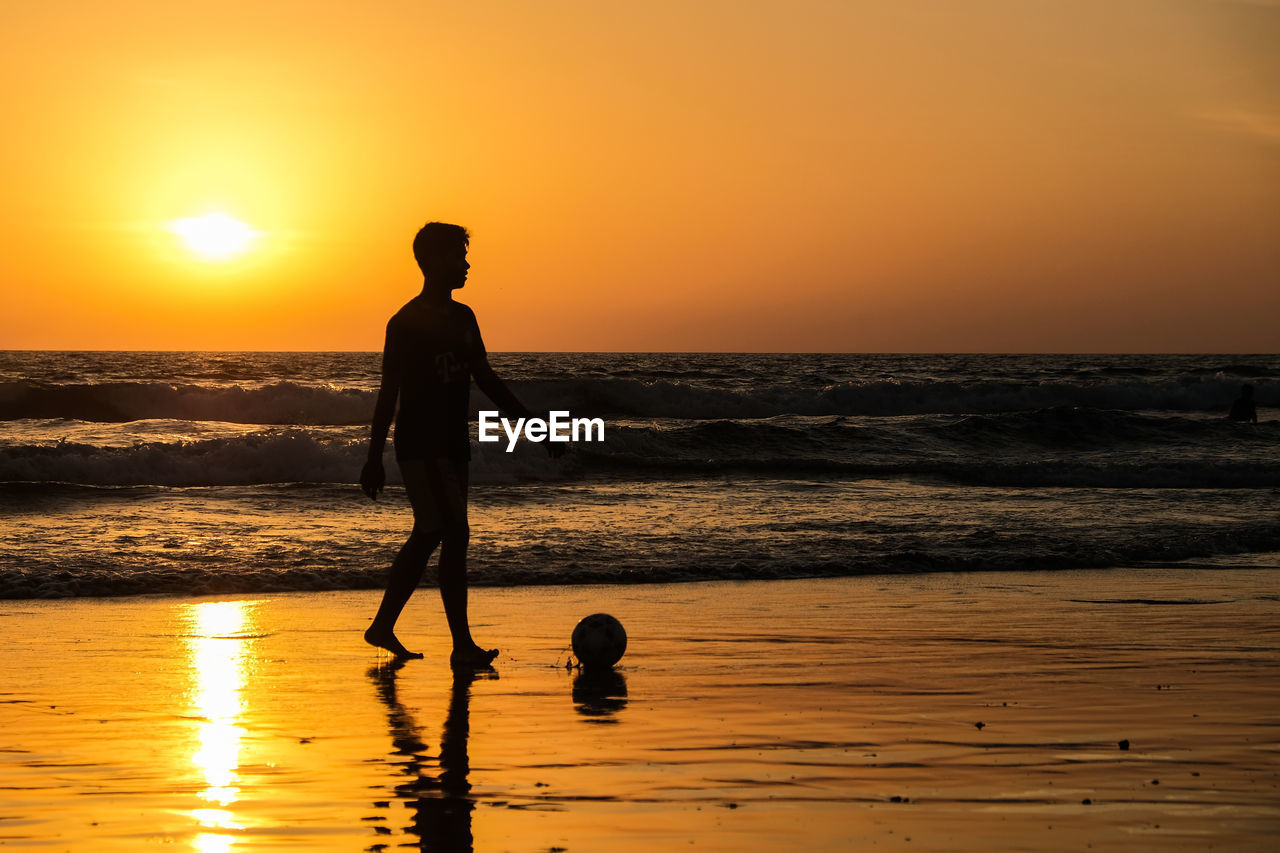 Silhouette man standing on beach against sky during sunset. seminyak bali