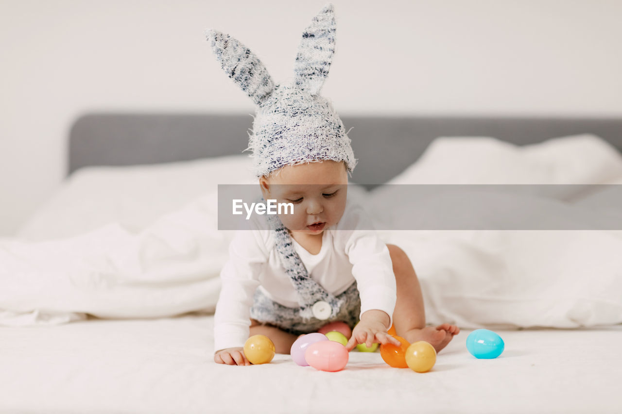 Cute boy playing with toys sitting on bed at home